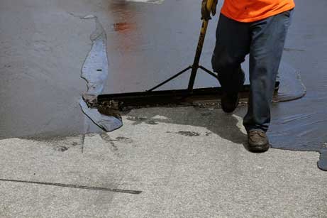 Asphalt contractor spreading a sealcoating mix over an existing driveway. Picture taken in Fort Lauderdale, Florida